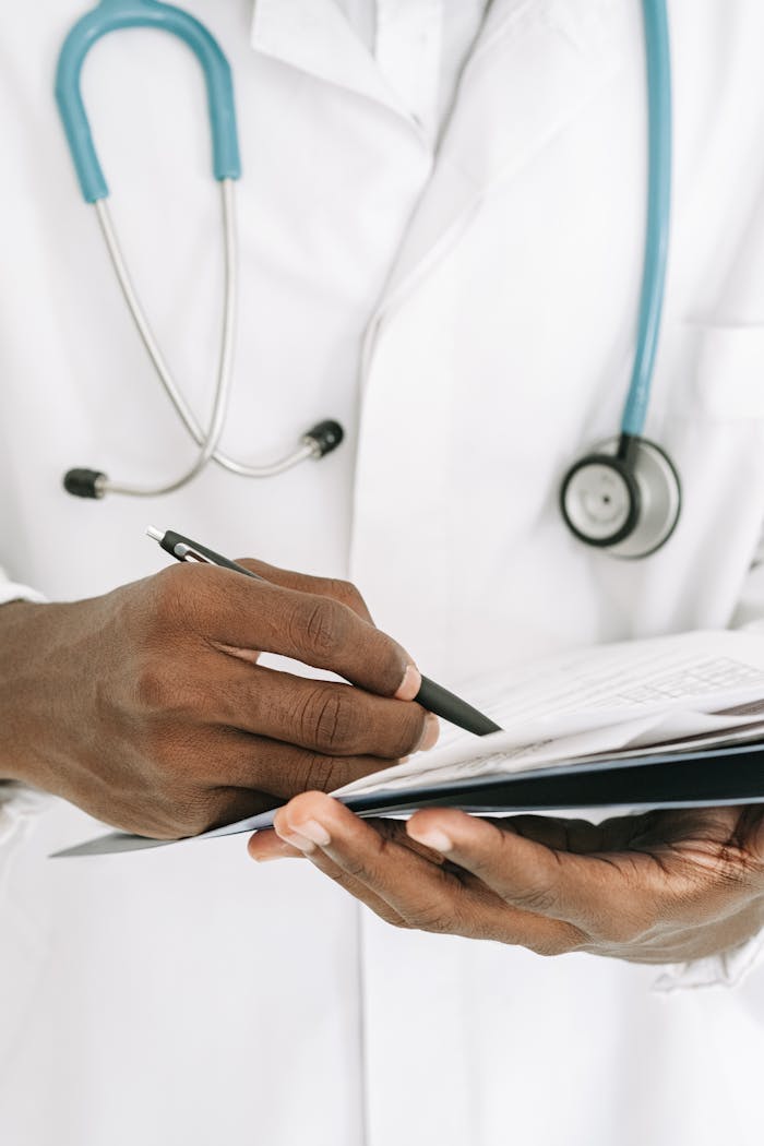 Close-up of a doctor writing on a notepad, wearing a stethoscope around the neck.